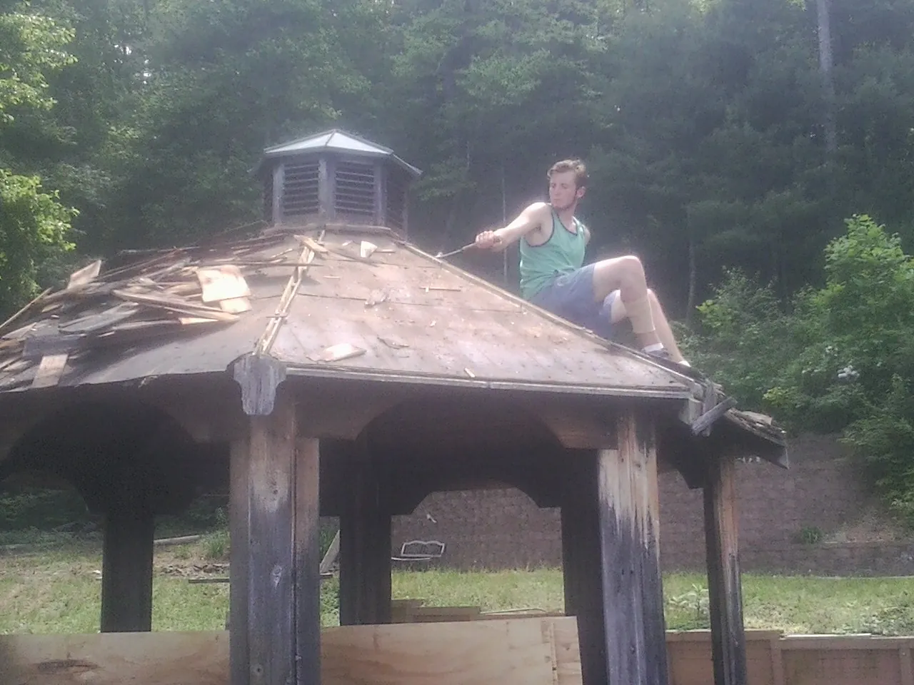 Tearing the old roof off a wooden gazebo before new shakes in Auburntown