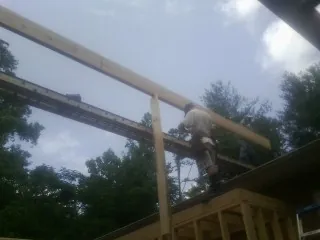 Carpenter setting a ridge beam over a new addition frame — Ice Dam Removal by Roofing Brothers in Auburntown