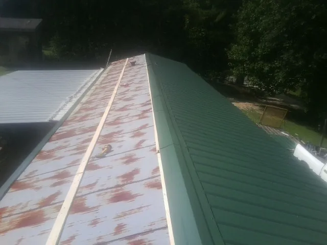 Old rusted panels beside newly installed green metal roofing — Wind Damage Roof Repair by Roofing Brothers in Auburntown