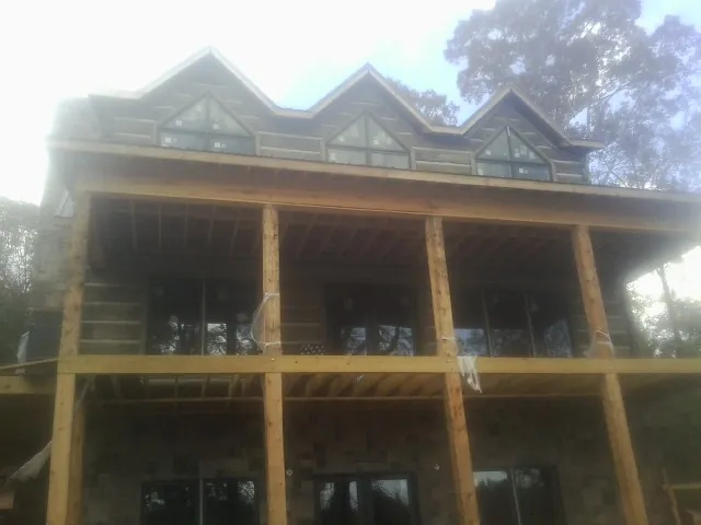 Dormers and porch framing on a large log home under construction — Roof Coating work by our crew in Auburntown