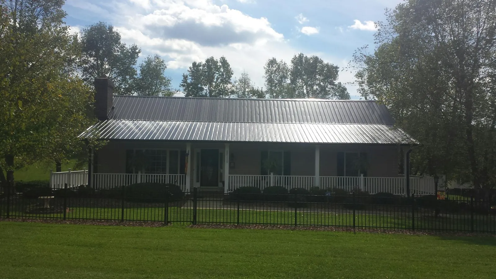 Gray metal roof on a brick ranch with a full width front porch — Gutter Guard Installation work by our crew in Auburntown