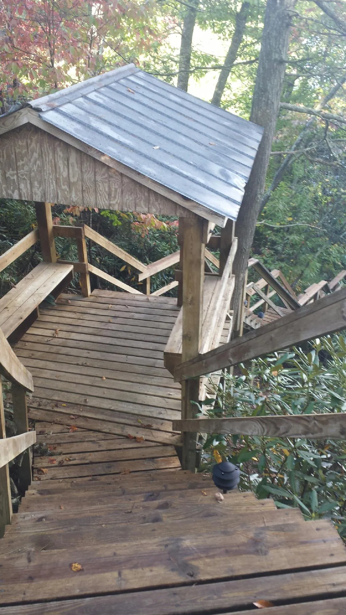 Metal roofed shelter over wooden steps on a wooded walkway — Skylight Repair & Installation work by our crew in Auburntown