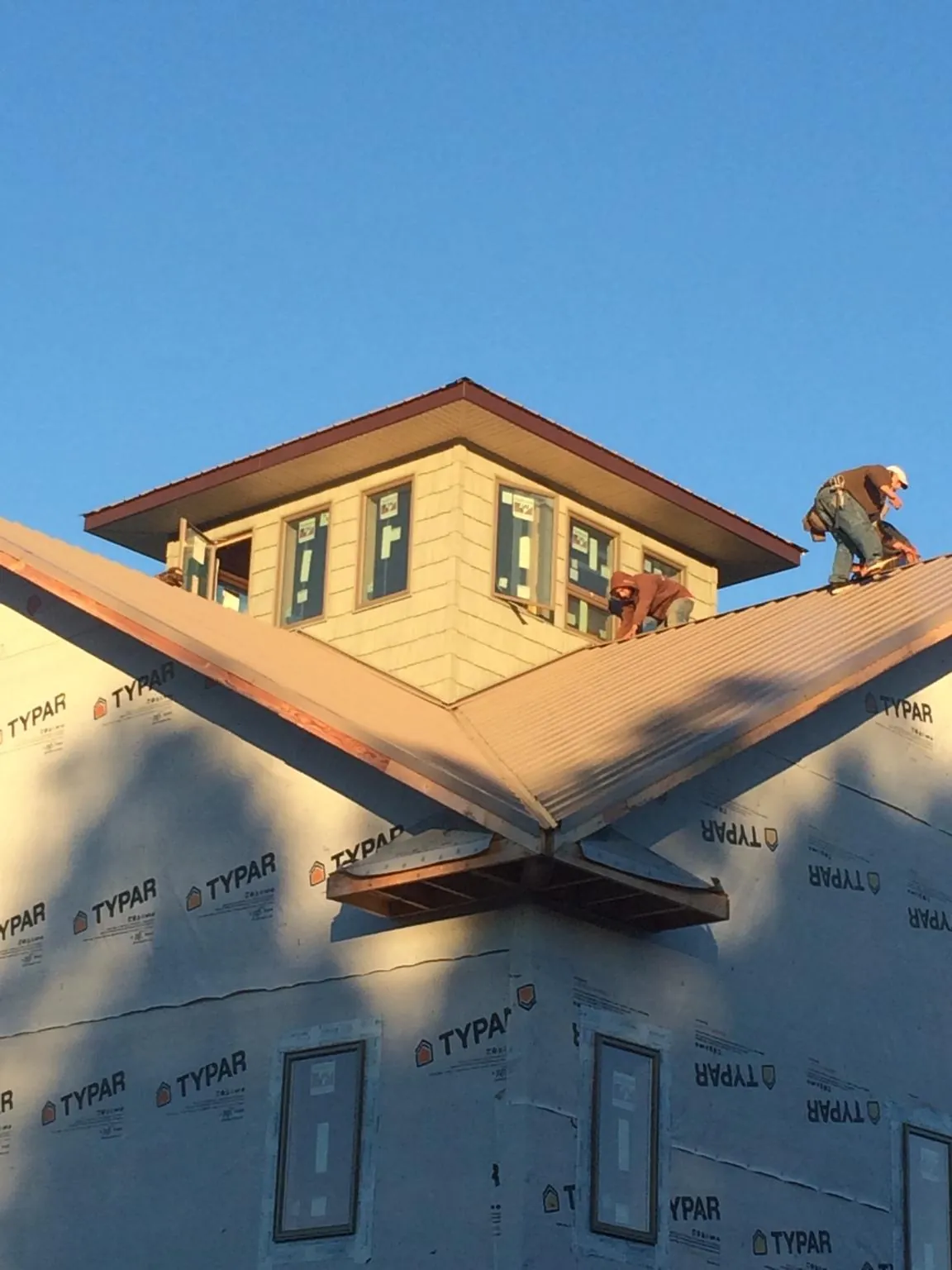 Roofers working around a rooftop cupola on a new metal roof at sunset — Roof Waterproofing in Auburntown by Roofing Brothers